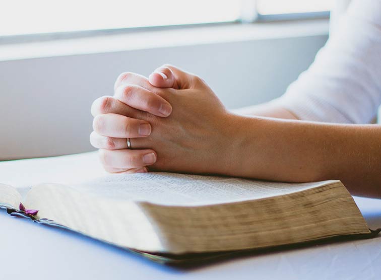 Frau betet über Bibel.